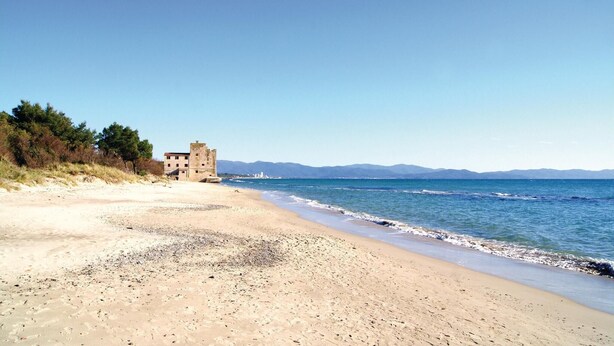 A beach with a historic stone building on the left and a clear blue sky. - Beautiful home in Gavorrano GR with WiFi (Gavorrano GR)