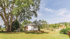 A white house with a red roof, surrounded by a grassy yard and large trees. - Beautiful home in Gavorrano GR with WiFi (Gavorrano GR)