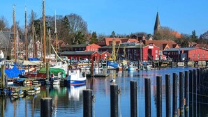 Un port avec des bateaux, une église et des bâtiments rouges.