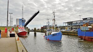 Een haven met twee boten, een rode genaamd 'EMILE, ROBIN' en een blauwe met 'RI 192' erop, afgemeerd in de buurt van een gebouw met de tekst 'Restaurant KommandoBrewery'.