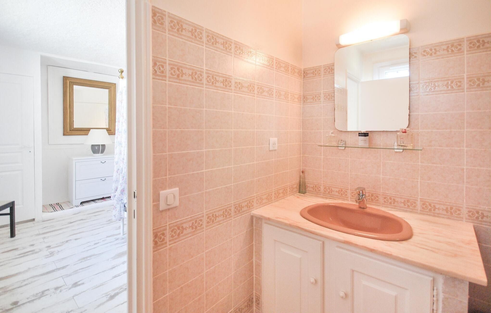 Une salle de bain avec un lavabo beige, un miroir et des carreaux à motifs.