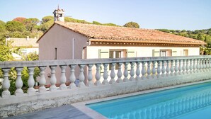 A pool with a white balustrade, a building with a tiled roof, and a view of trees and hills in the background. - Lovely home in Sainte Maxime (Sainte Maxime)