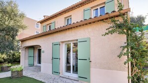 A two-story building with green shutters, a stone-paved entrance, and a garden with plants. - Lovely home in Sainte Maxime (Sainte Maxime)