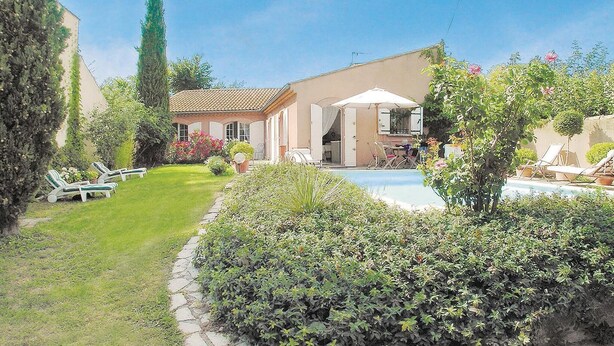 Ein Haus mit Schwimmbecken, umgeben von einem gepflegten Garten und einigen Liegestühlen.