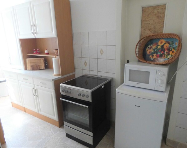 Una cocina con estufa, microondas y armarios.
