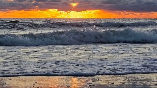 A sunset over the ocean with waves.