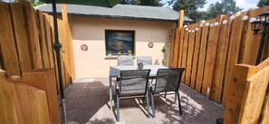 Un patio con tavolo e sedie, una recinzione in legno e un muro decorativo.