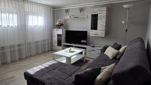 A living room with a sofa, coffee table, TV, and curtains.