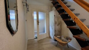 A staircase leading to a second floor, a mirror on the wall, and a small table with papers.