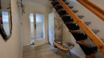 Eine Treppe führt zu einer zweiten Etage, ein Spiegel an der Wand und ein kleiner Tisch mit Papieren.