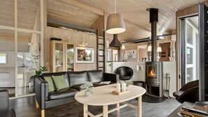 A modern living room with a black leather sofa, a round wooden coffee table, and a large fireplace.