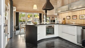 A modern kitchen with a central island, stainless steel appliances, and wooden paneling.