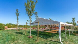 A tented outdoor dining area with tables and chairs, surrounded by greenery and trees. - Pet friendly apartment in Castiglion del Lago PG with outdoor swimming pool (Castiglion del Lago PG)