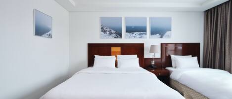 Ein Hotelzimmer mit einem großen Bett, zwei Nachttischen, einem Beistelltisch und drei gerahmten Bildern an der Wand.