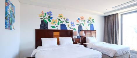 Habitación de hotel con dos camas, un ventanal grande y un mural floral en la pared.