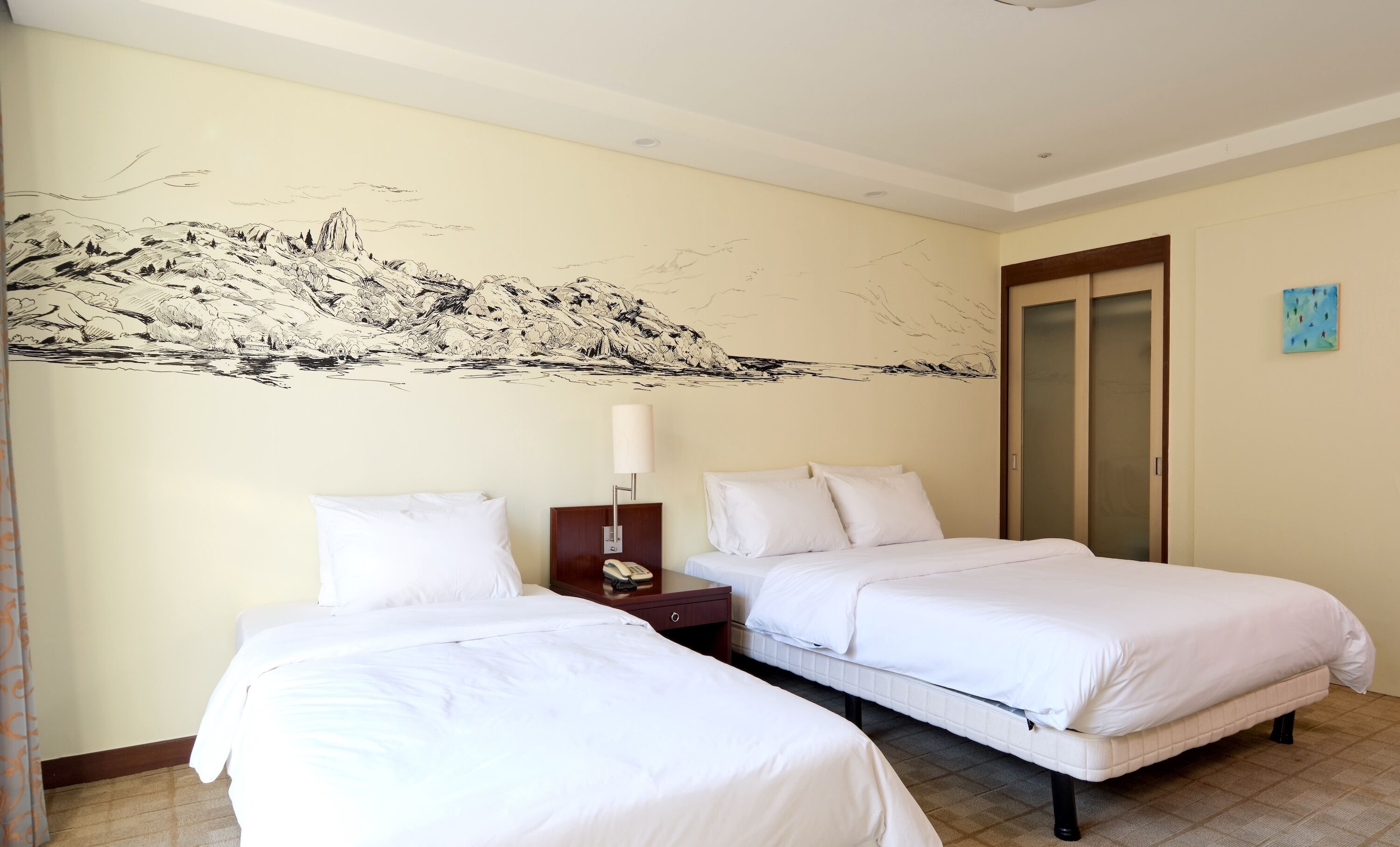Una habitación de hotel con dos camas, una mesita de noche, una lámpara y un cuadro en la pared.