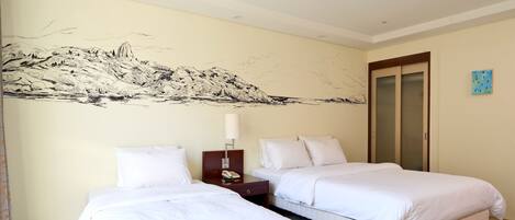 Una habitación de hotel con dos camas, una mesita de noche, una lámpara y un cuadro en la pared.