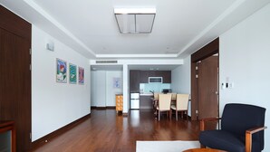 Amplia sala de estar con piso de madera, comedor con mesa y sillas, y cocina al fondo.