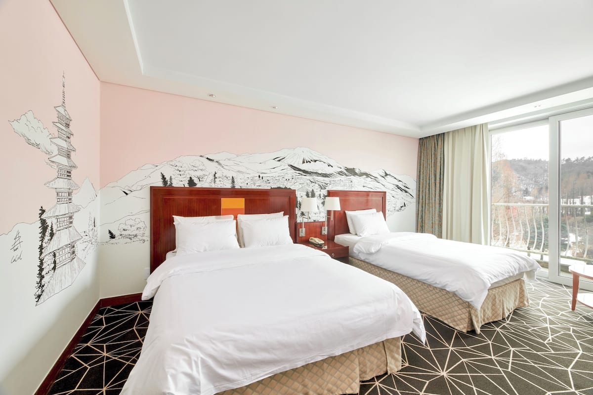 A hotel room with two beds, a large window, and a mural of a mountain and pagoda.