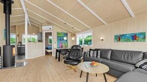 A modern living room with a fireplace, a sofa, a dining area, and artwork on the walls. - Cozy home in Haderslev with kitchen (Haderslev)