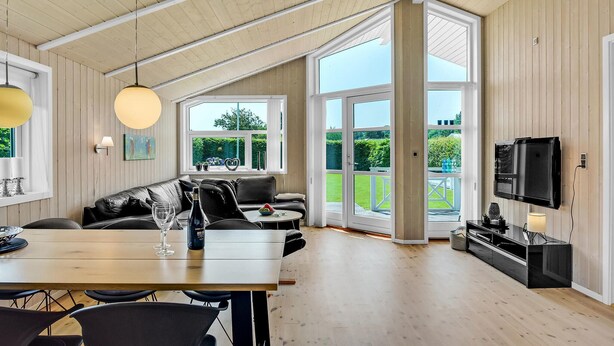 A spacious living area with a high ceiling, a dining table, a sofa, and a television. - Cozy home in Haderslev with kitchen (Haderslev)