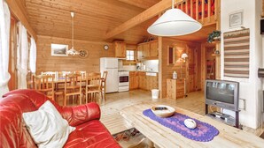 Ein gemütliches Blockhaus-Interieur mit einer roten Ledersofa, einem Holzesstisch und einem Fernseher.