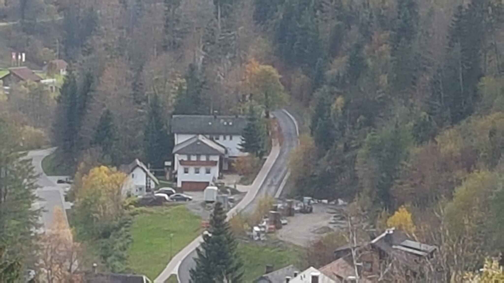 Et boligområde med et hus omgivet af træer og en snoet vej.