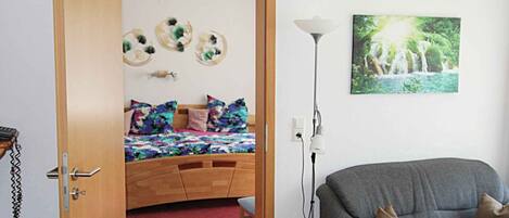 A bedroom with a bed, a bedside lamp, a sofa, and a wall-mounted picture.