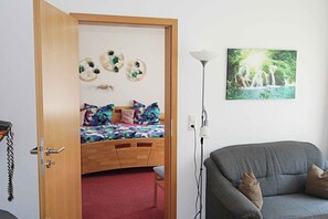A bedroom with a bed, a bedside lamp, a sofa, and a wall-mounted picture.