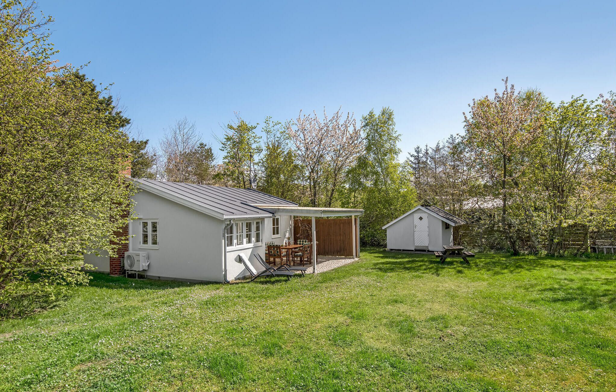 A single-story house with a covered patio, a small shed, and a lawn.