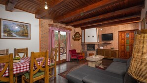 Una sala de estar acogedora con chimenea, televisor y comedor con manteles a cuadros.