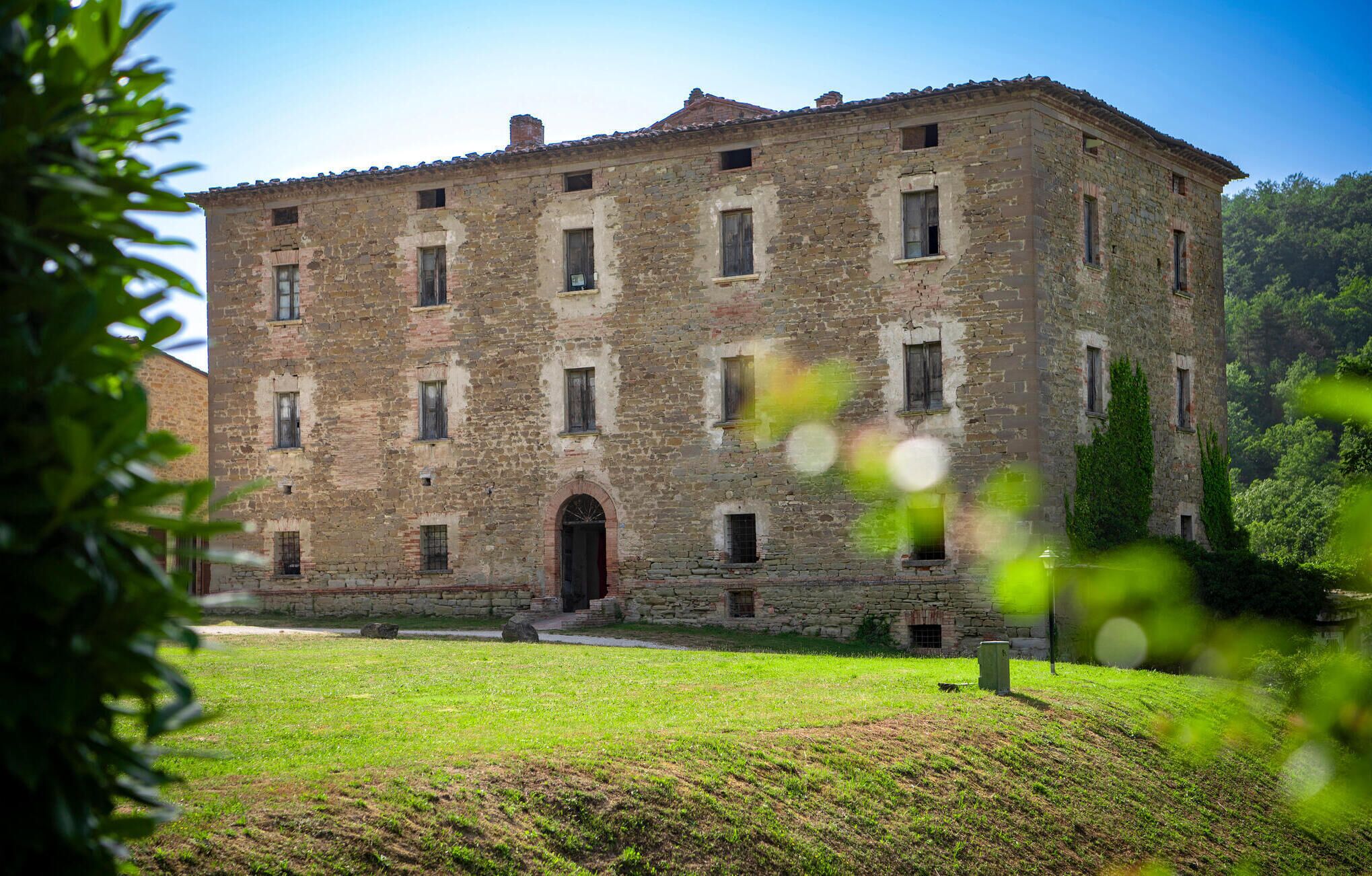 A large, historic stone building with multiple windows and a central entrance.