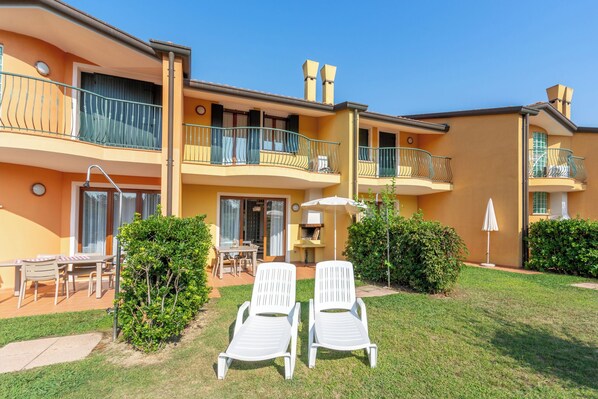 A two-story building with balconies, outdoor seating, and a well-maintained lawn. - Holiday Home with Pool and Terrace (Albarella)