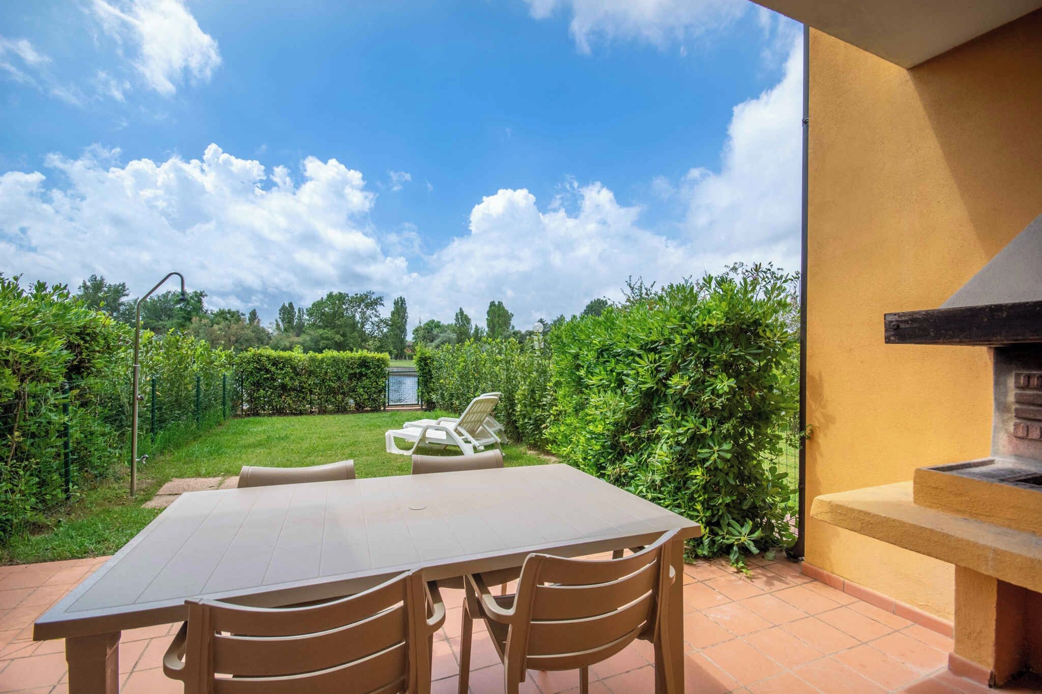 Une terrasse extérieure avec une table et des chaises, entourée de verdure et sous un ciel dégagé.