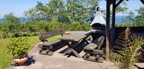 Een terras met een barbecue, een houten tafel en een bloempot.