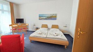Habitación de hotel con cama, escritorio con silla, televisor y un cuadro en la pared.
