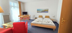 Et hotelværelse med seng, skrivebord med stol, fjernsyn og et maleri på væggen.