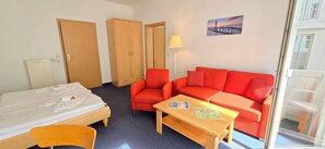 Een hotelkamer met een bed, een rode bank, een houten tafel en een lamp.