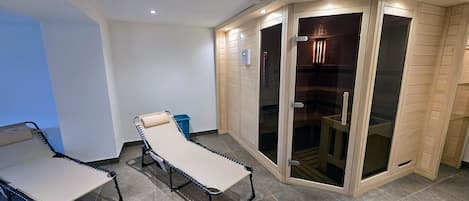 A room with a massage table, a small bench, and a sliding glass door leading to a shower area.