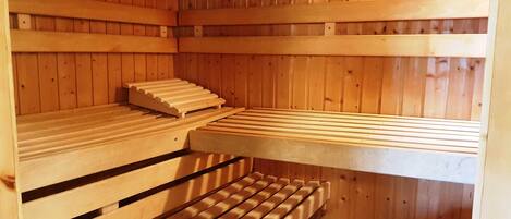 Eine Sauna mit Holzbänken und leicht abschüssigem Boden.