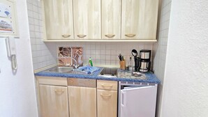 Una cocina compacta con un lavamanos, una cafetera y un lavavajillas.