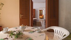 Un coin repas avec une table dressée pour deux personnes, une théière blanche, deux tasses et un arrangement floral.