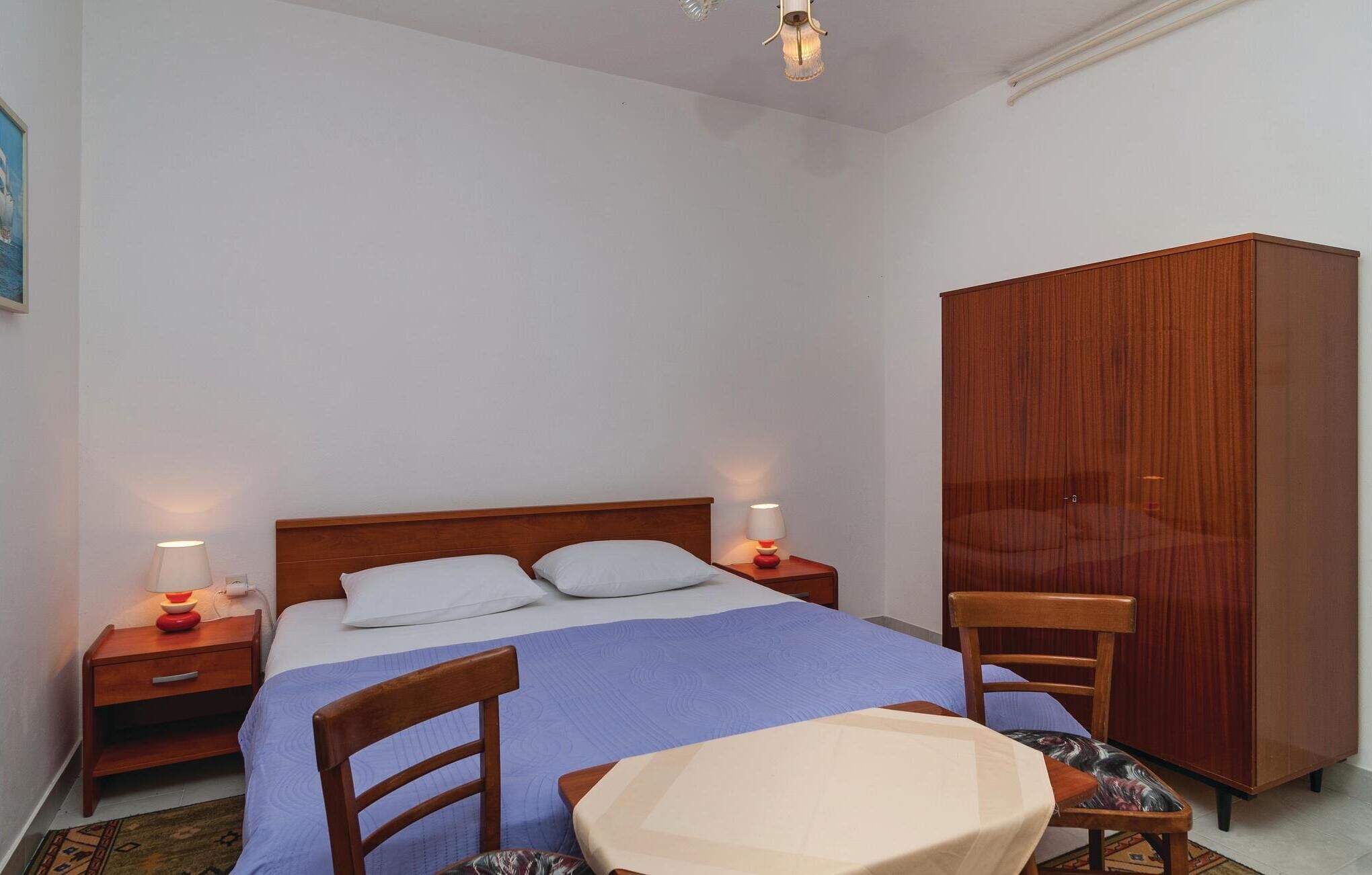 Une chambre à coucher avec un lit, deux tables de chevet avec des lampes, une armoire et une chaise.