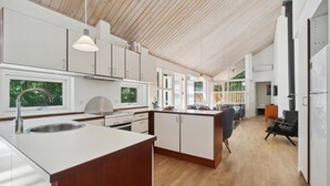 A modern kitchen with a central island, wooden flooring, and large windows providing natural light. - Stunning home in Hasle with sauna (Hasle)