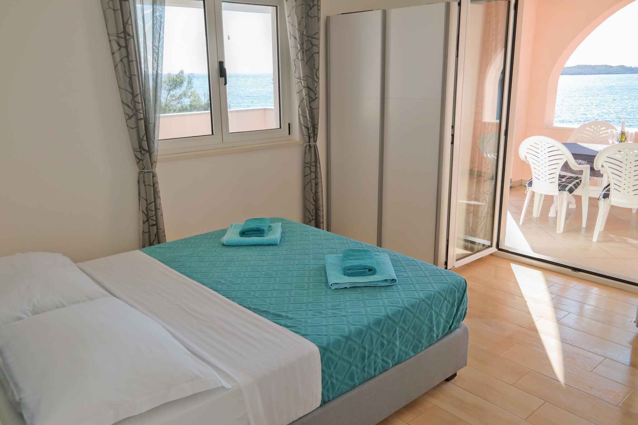 A bedroom with a bed, a window, and a view of the sea.