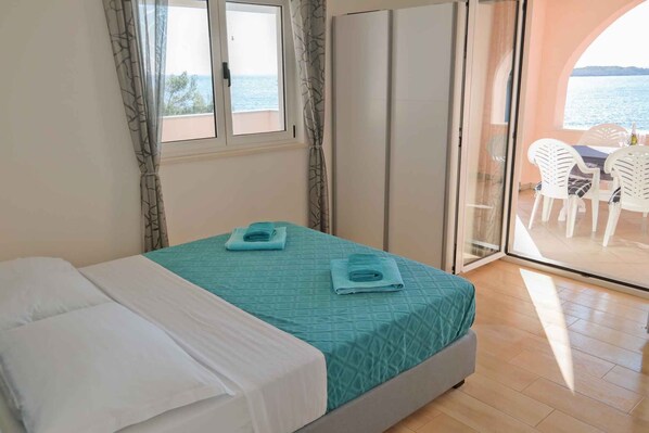 A bedroom with a bed, a window, and a view of the sea.