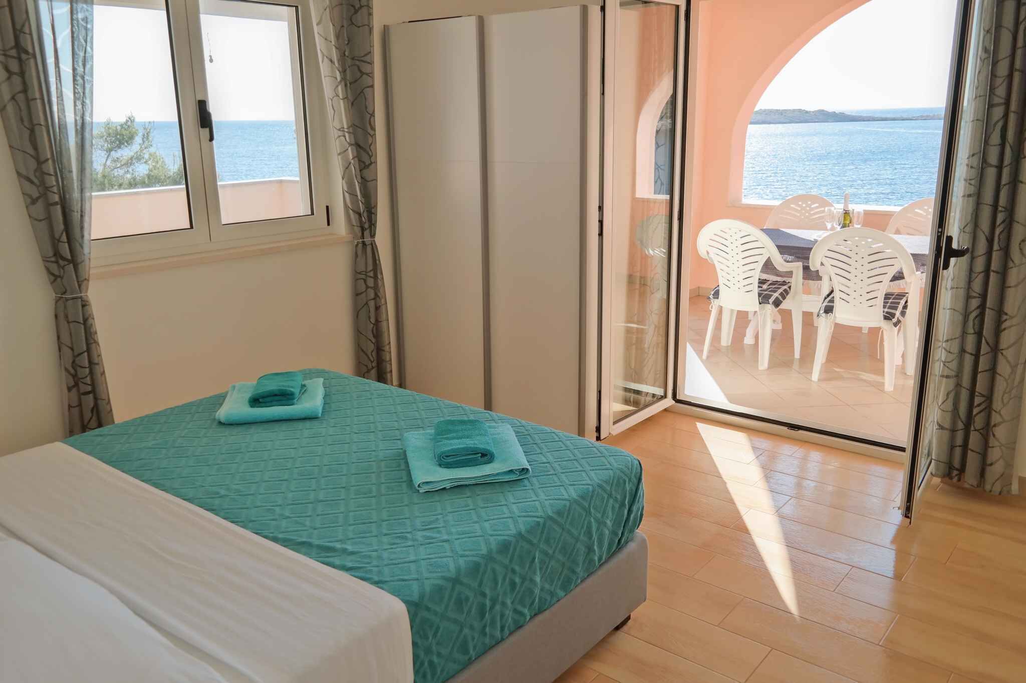 A bedroom with a bed, a view of the sea, and a balcony with chairs.