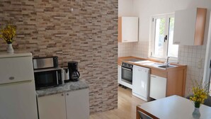 A compact kitchen with white cabinets, a microwave, a coffee maker, and a sink.