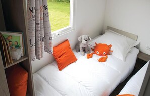 A neatly made bed with white bedding and orange pillows, a small stuffed dog, and a crab toy on the bed. - Awesome home in Hvide Sande with WiFi (Hvide Sande)