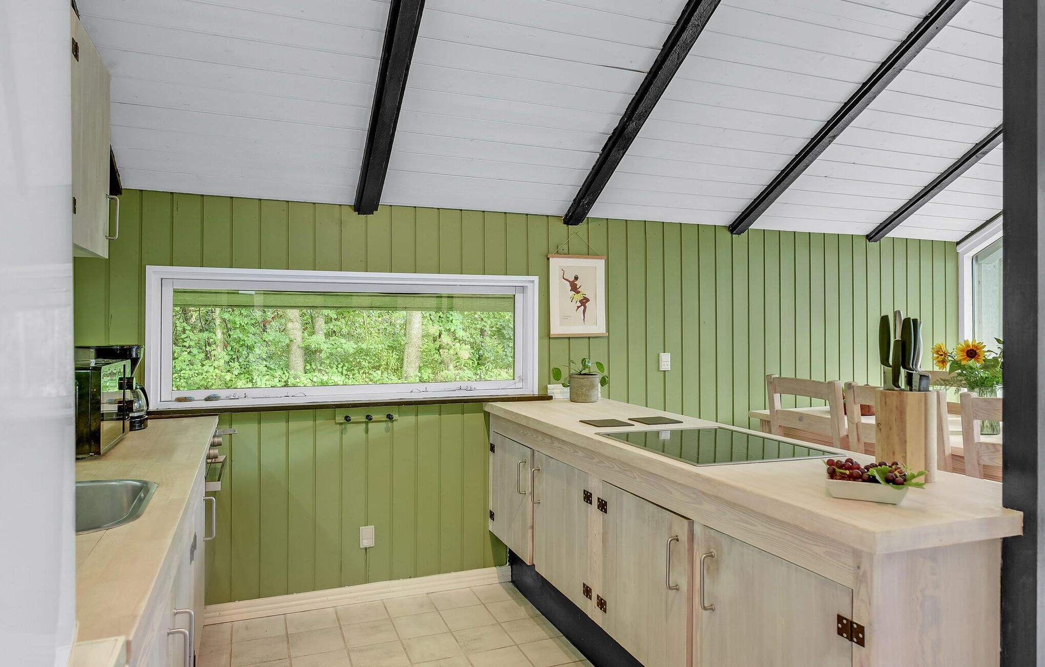 A kitchen with a window, green walls, and a wooden countertop.